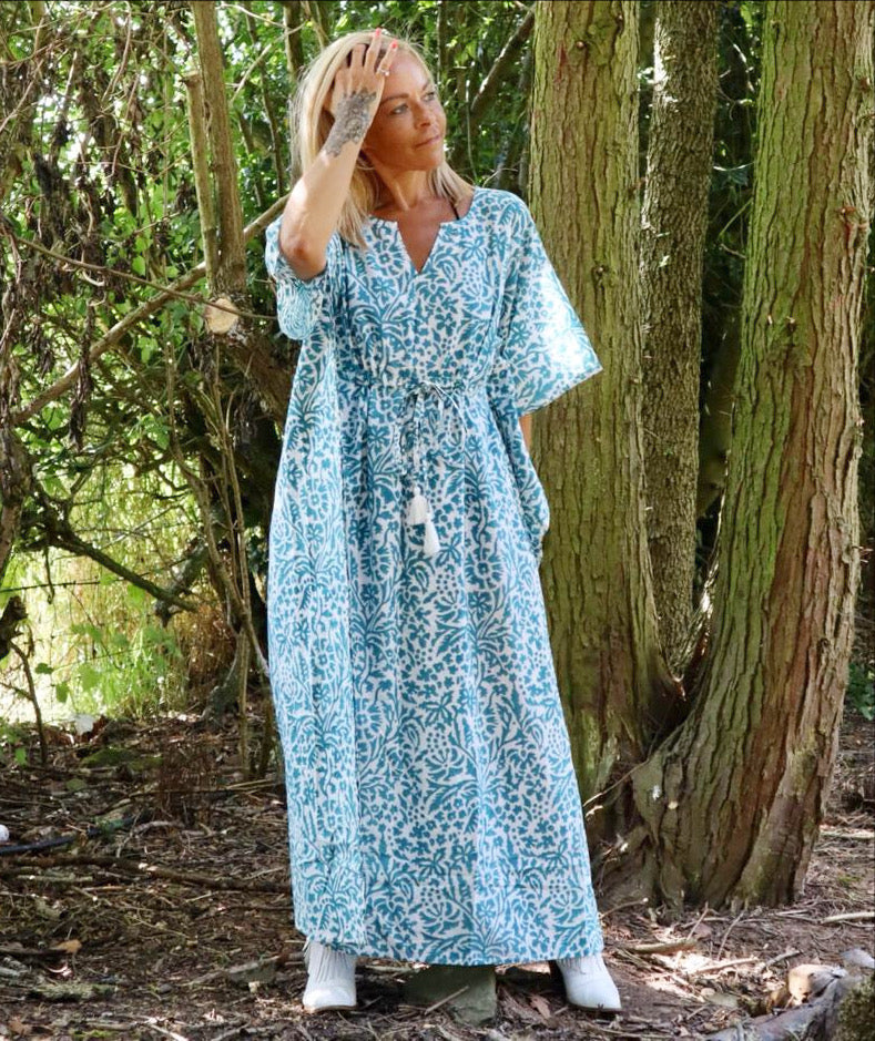 Woman standing outdoors among trees wearing an Eden bohemian printed cotton teal maxi kaftan//dress free size with a flowing boho style and intricate pattern.