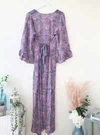 Bluebell lilac vintage-silk free-size ruffled-sleeved tie maxi dress in soft lilac paisley pattern, hanging against a light background with floral and rustic decor accents.