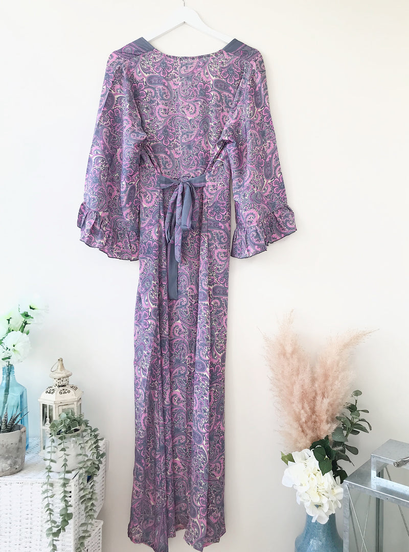 Bluebell lilac vintage-silk free-size ruffled-sleeved tie maxi dress in soft lilac paisley pattern, hanging against a light background with floral and rustic decor accents.