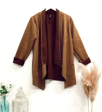 Faux-suede boho waterfall tan jacket displayed on a hanger with contrast trim, featuring a draped open front and long sleeves in a cozy boho style.