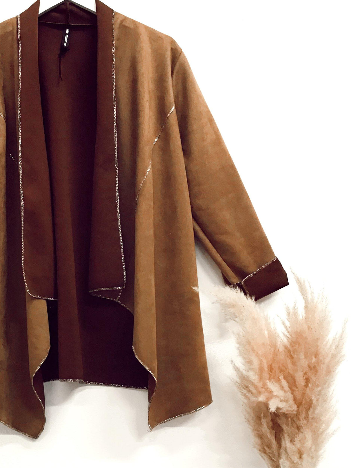 Faux-suede boho waterfall tan jacket with soft draping and contrast stitching, styled in a casual bohemian look against a white background with pampas grass.